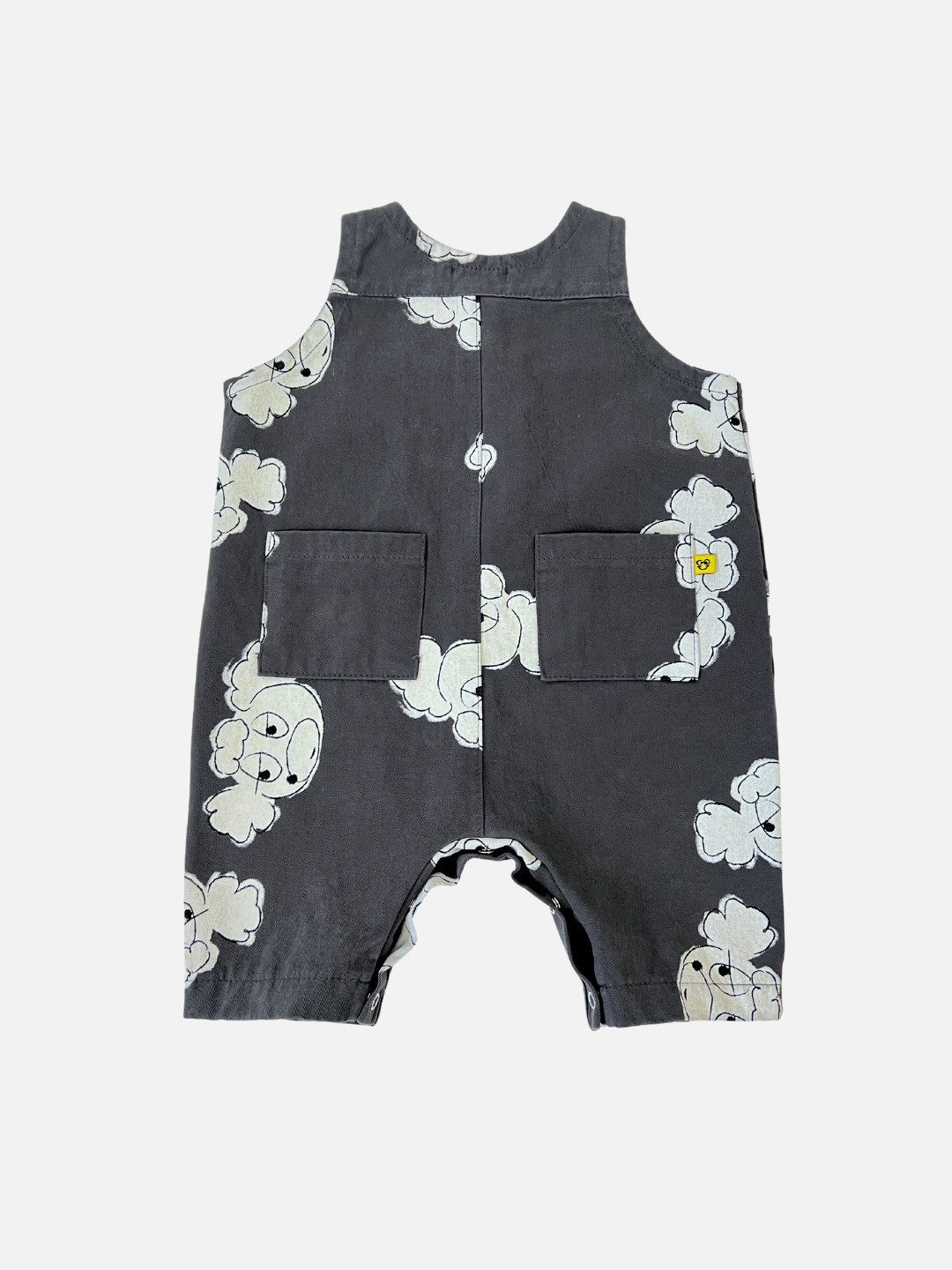 The POODLE OVERALL is a dark gray baby romper with a poodle doodle print and white cartoon clouds, featuring two front pockets. This stylish piece from a Korean kids label is displayed laid flat on a white background.