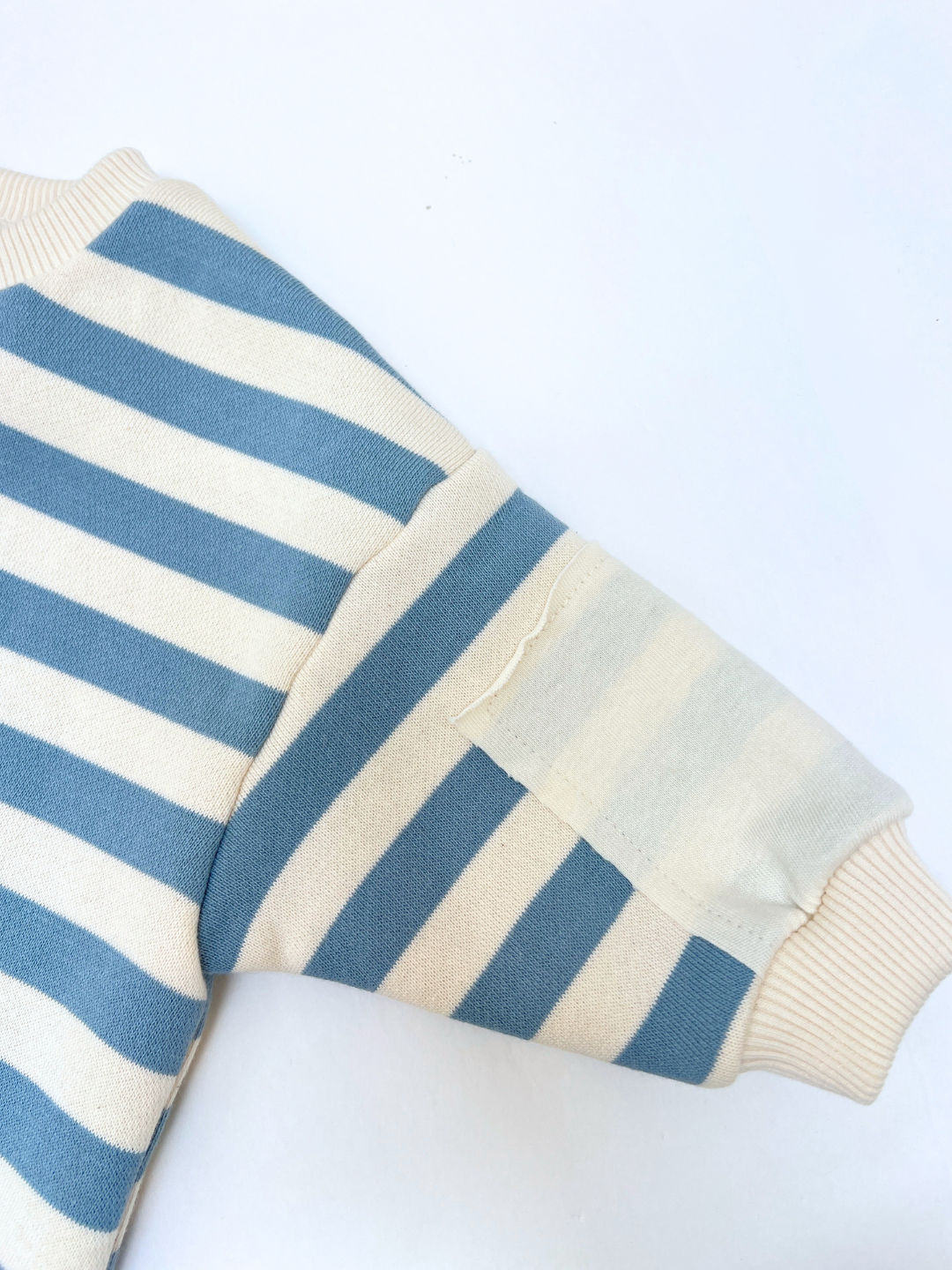 Close-up of a blue and white striped sweater sleeve on a white background