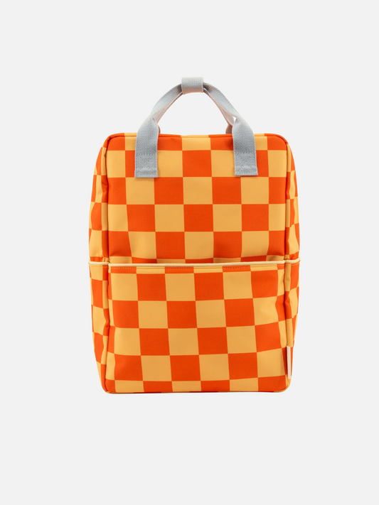 Image of The LARGE FARMHOUSE CHECKERBOARD BACKPACK, shown against a white background, features an orange and light yellow checkered pattern, two gray handles, a front pocket, waterproof lining, and is made from recycled PET bottles.