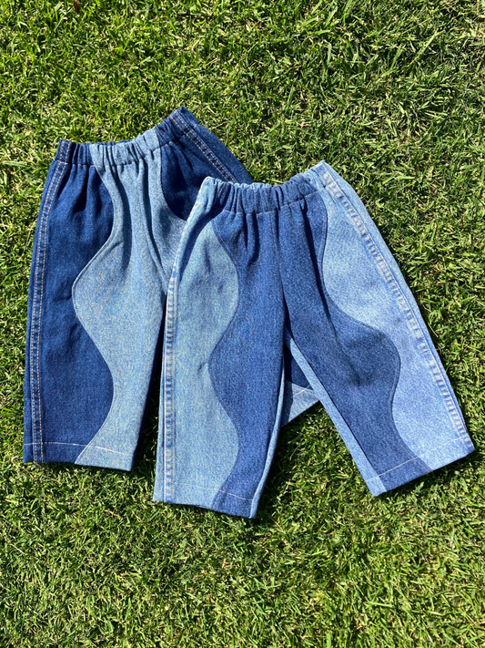Second image of Three pairs of the kid's up cycled wave jeans are laid flat on the quilt, all are one-of-a-kind made from second hand denim. 