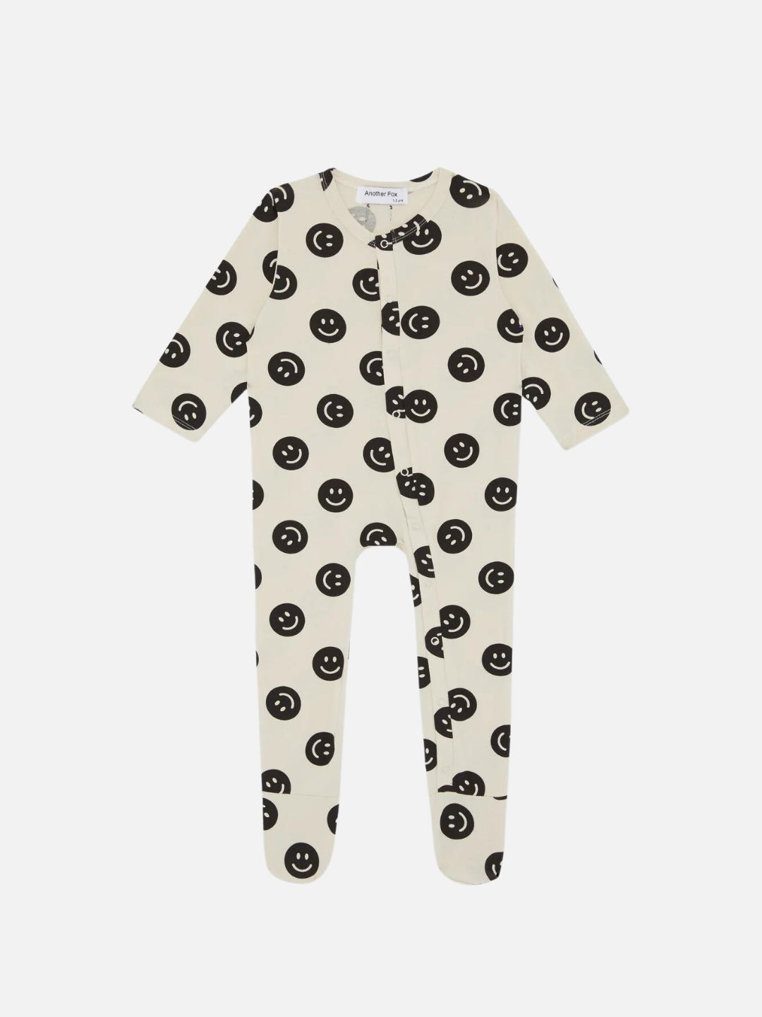 A front view of the cream colored, long sleeve, and full pant sleepsuit with a black smiley face pattern.