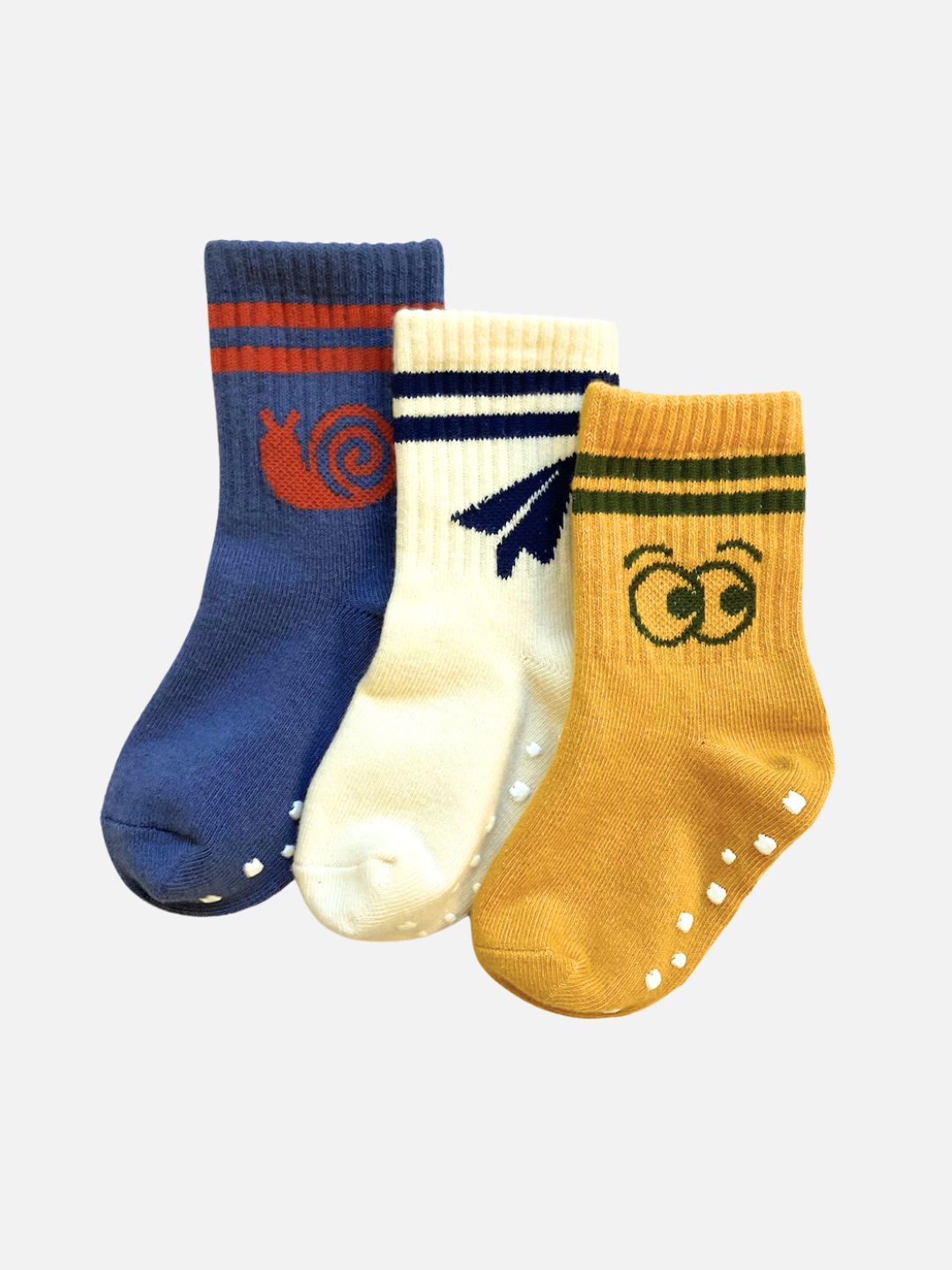 Three essential children's socks from the RIBBED GRIP SOCK SET on a plain background: a blue sock with a red snail, a white sock with a blue airplane, and a yellow ribbed sock with green eyes and stripes.