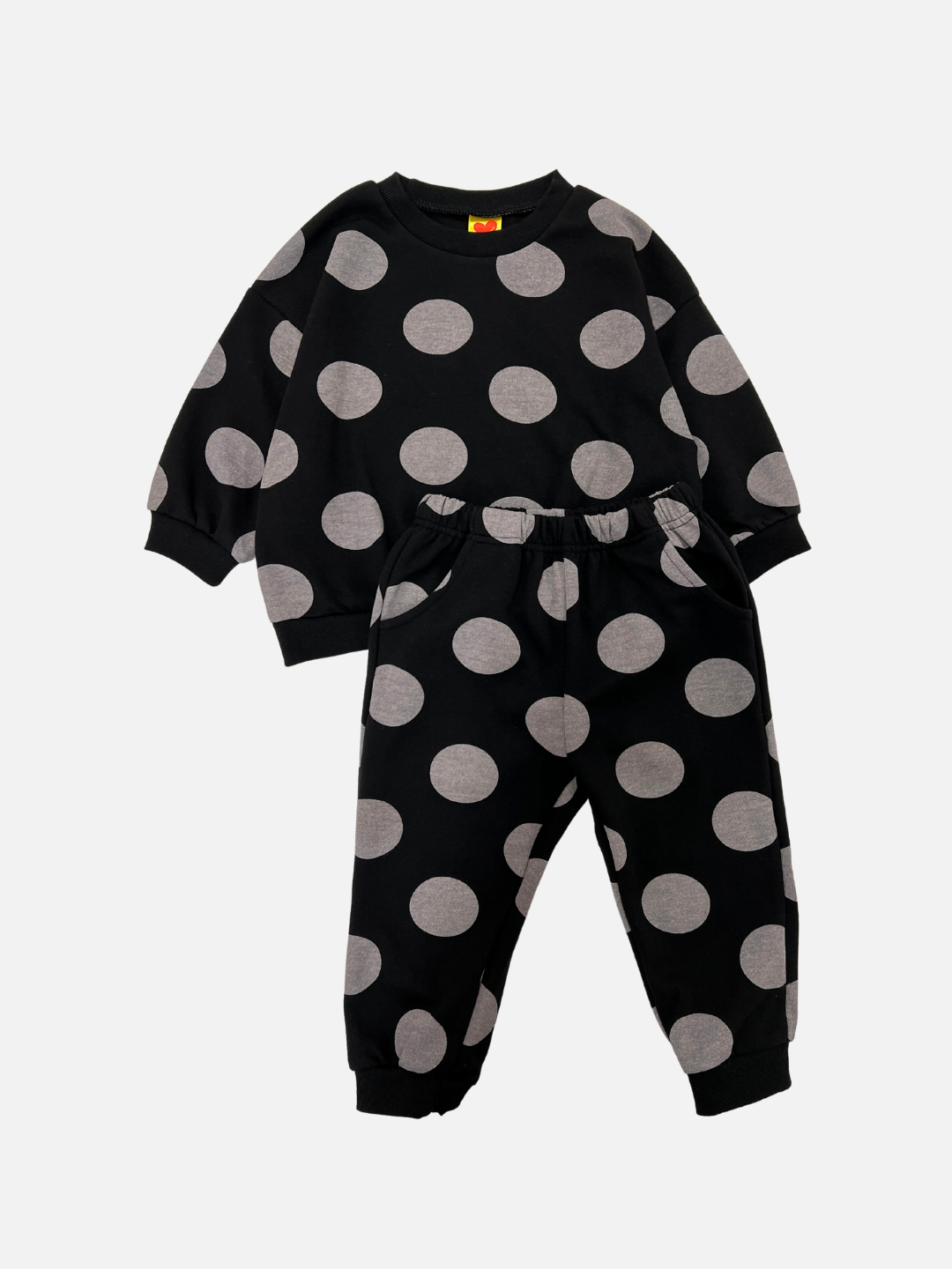 Front view of a kids sweat set in black with large grey polka dots. The set consists of a crewneck sweatshirt and a matching sweatpant.