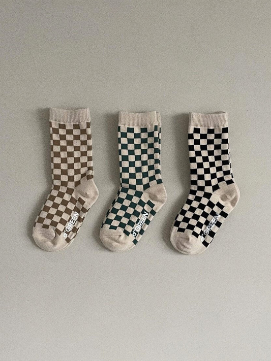 Second image of Set of three pairs of kids' checkerboard socks, in light brown, forest green, and black, on an ecru background