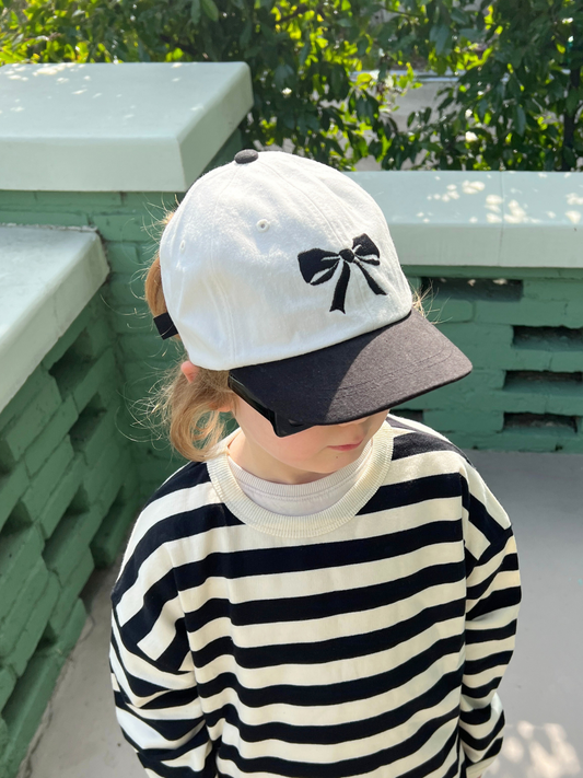 Second image of A front view of the kid's Bow Cap. White hat with black cap and black bow embroidery in the center. 