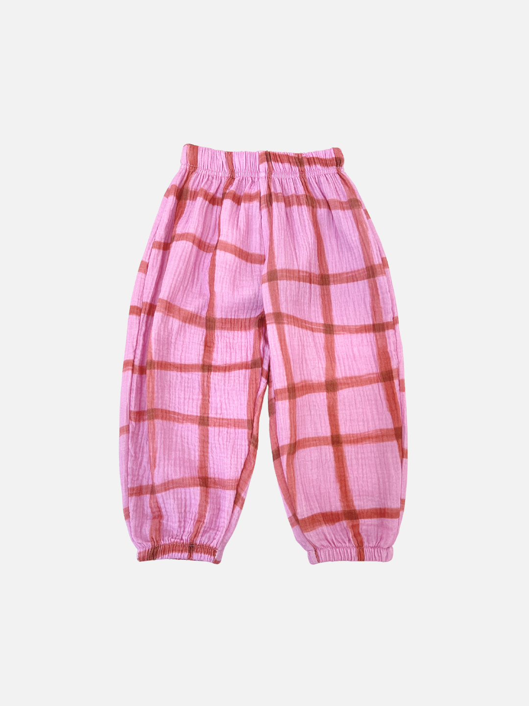 Pink/Terracotta | The PAINTBRUSH CHECK MUSLIN PANTS feature a hand-drawn grid check pattern in pink plaid, designed for toddlers. They include an elastic waistband and cuffs, all set against a plain white background.