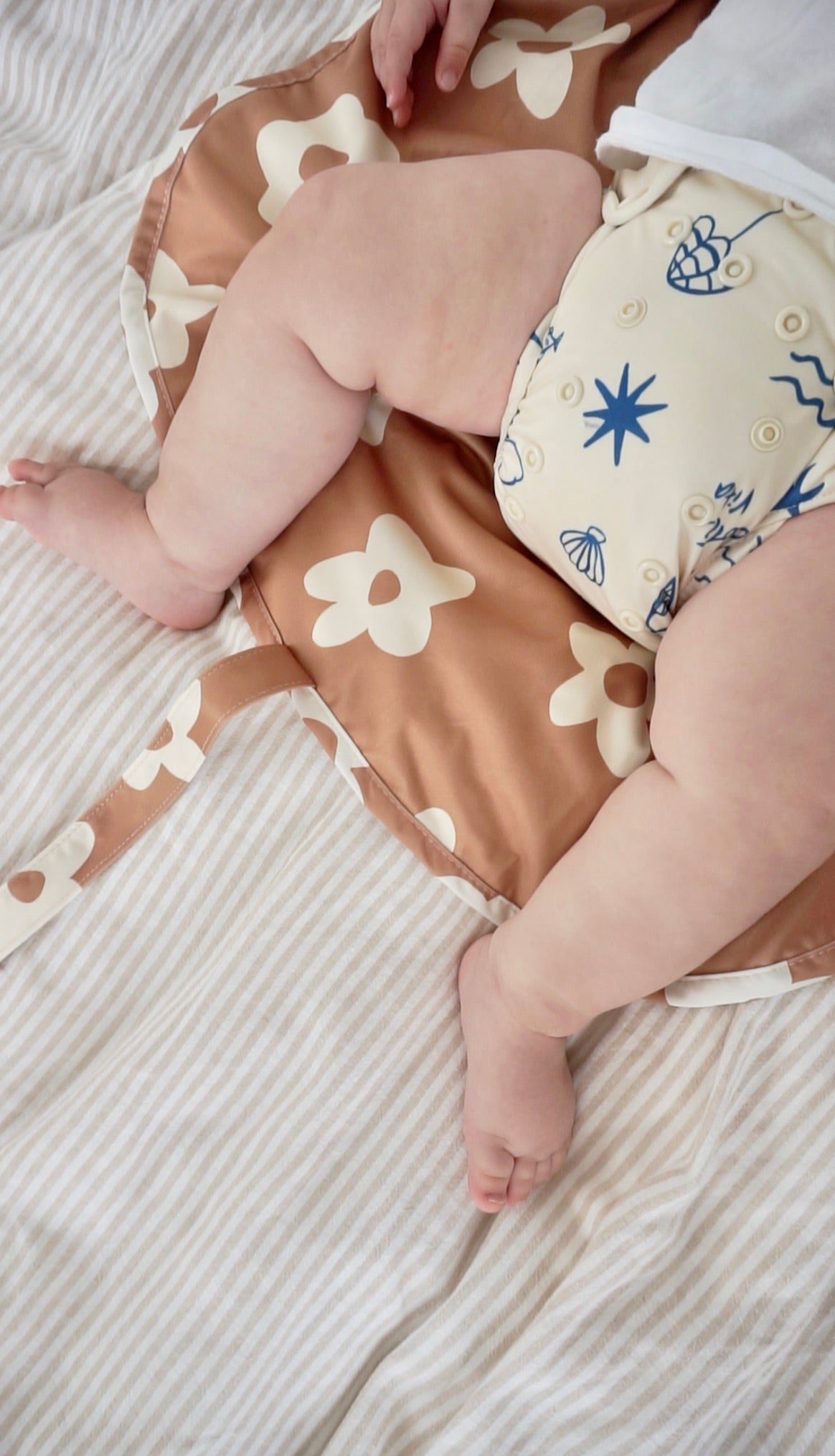 Baby in a swim diaper laying on the change mat in Posy print