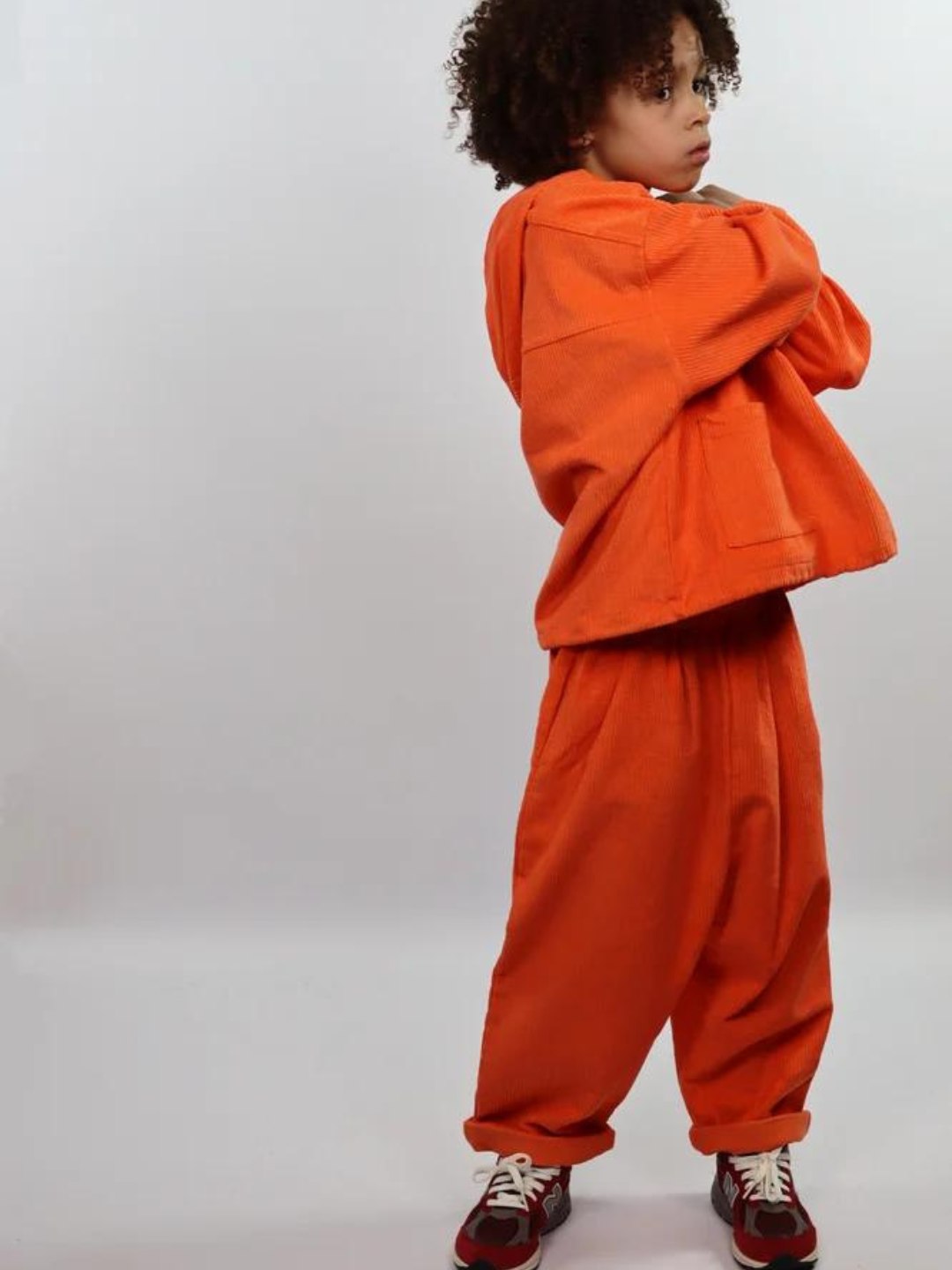 Child wearing orange kids' hooded smock and pants