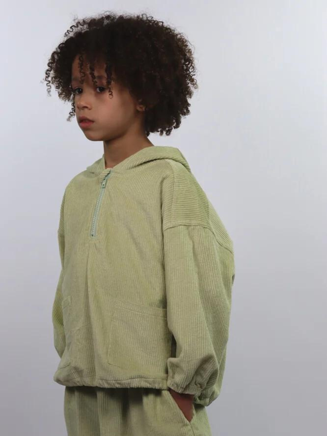 A child wearing a kids' hooded smock top in light pistachio green