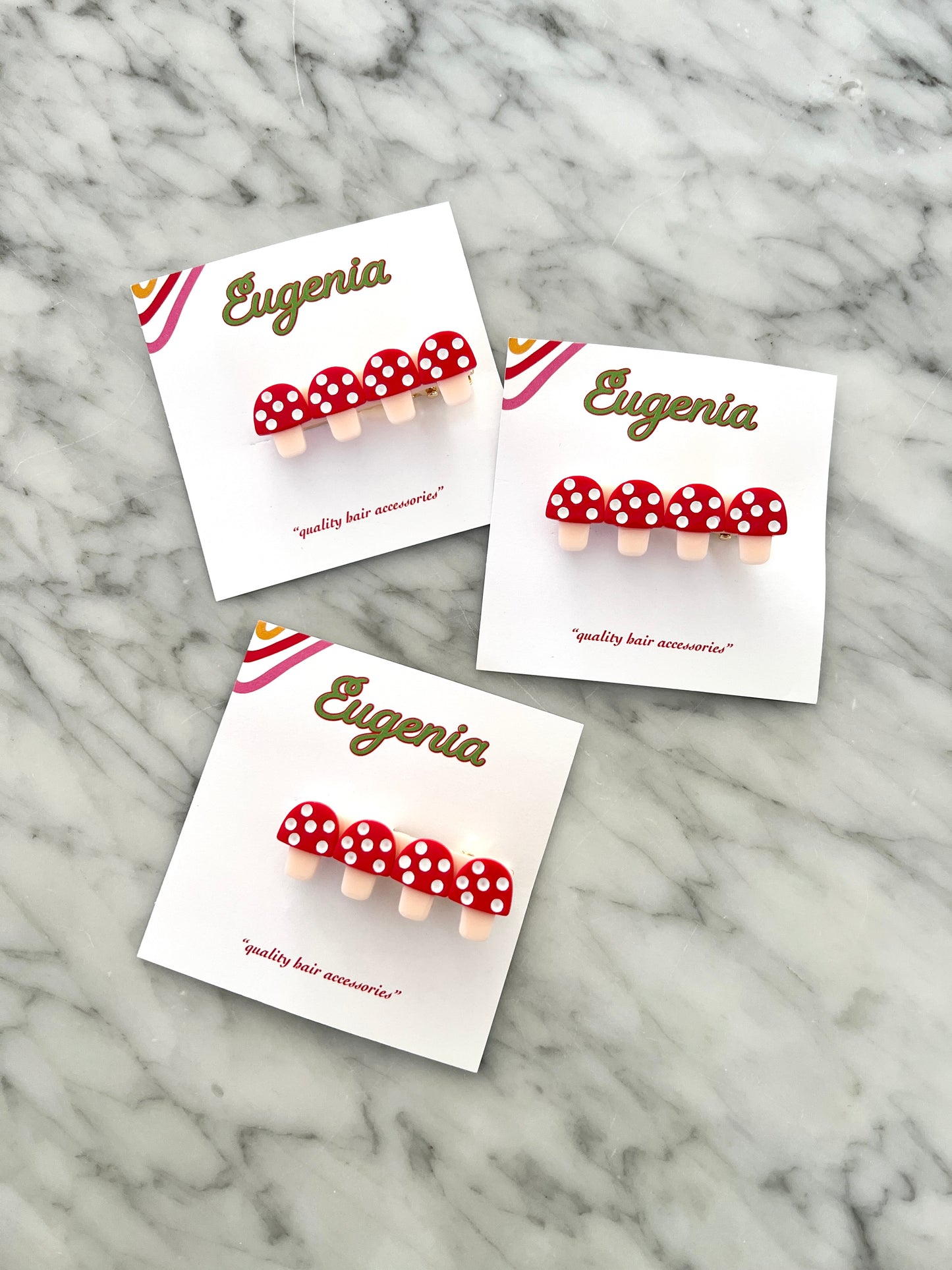 Three presentation cards of kids' barrettes, each featuring four red toadstools with white spots