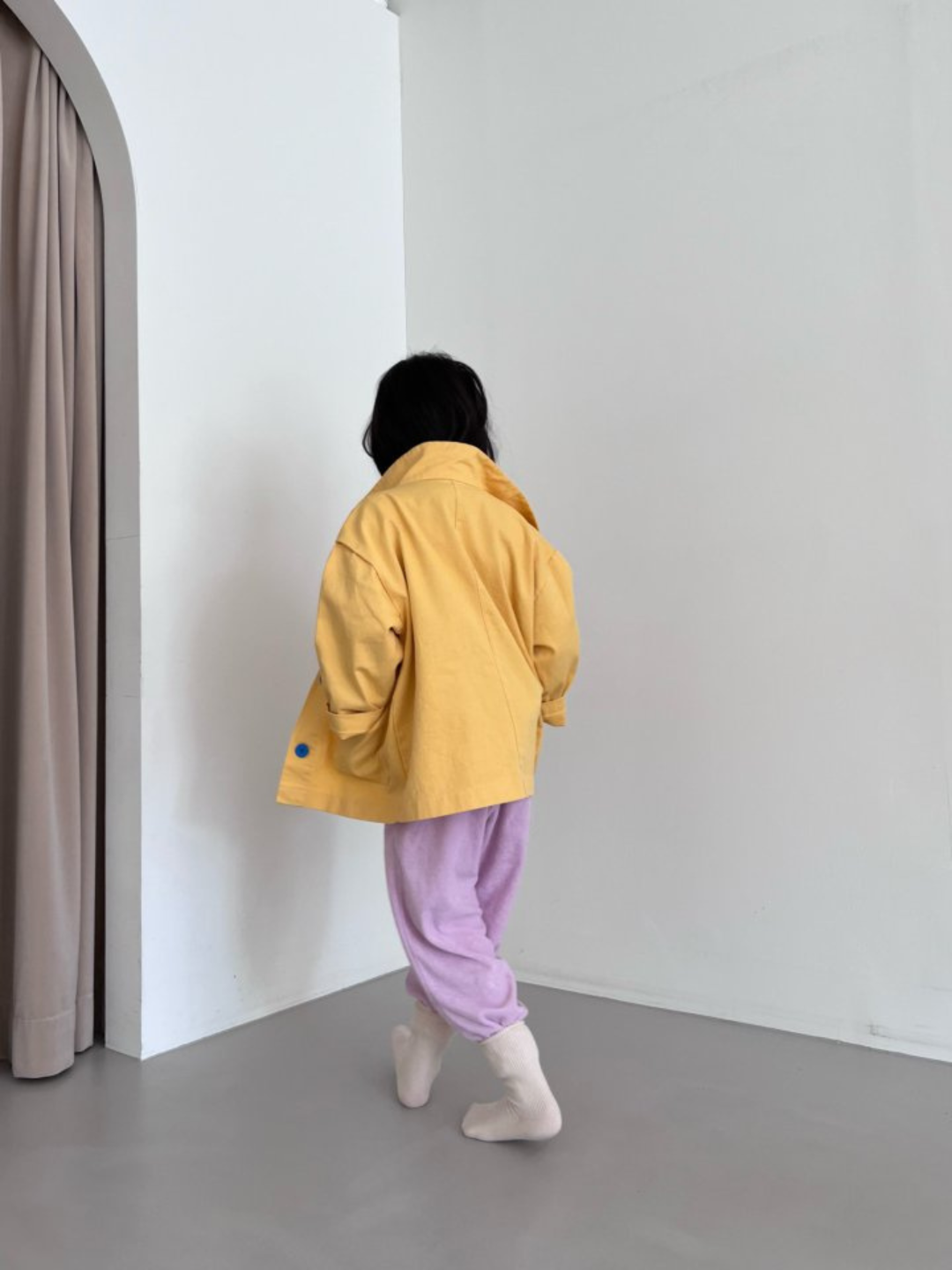 A child wearing a kids' jacket in yellow, back view
