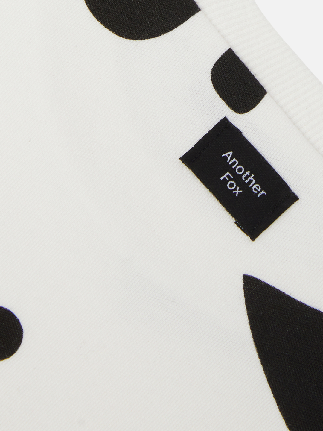 Close-up detail of the neck binding on a kids' tee black and white shirt, showing maker's label