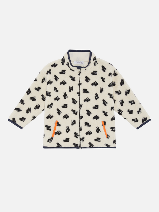 Image of A kids' jacket in a pattern of black scribbles on a cream background with orange pocket  bindings
