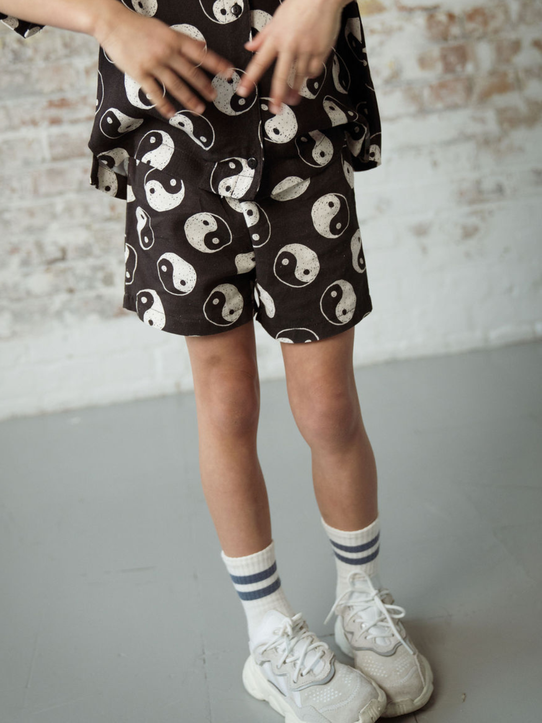 A front view of the elastic drawstring black shorts with a yin and yang pattern all over on a child.