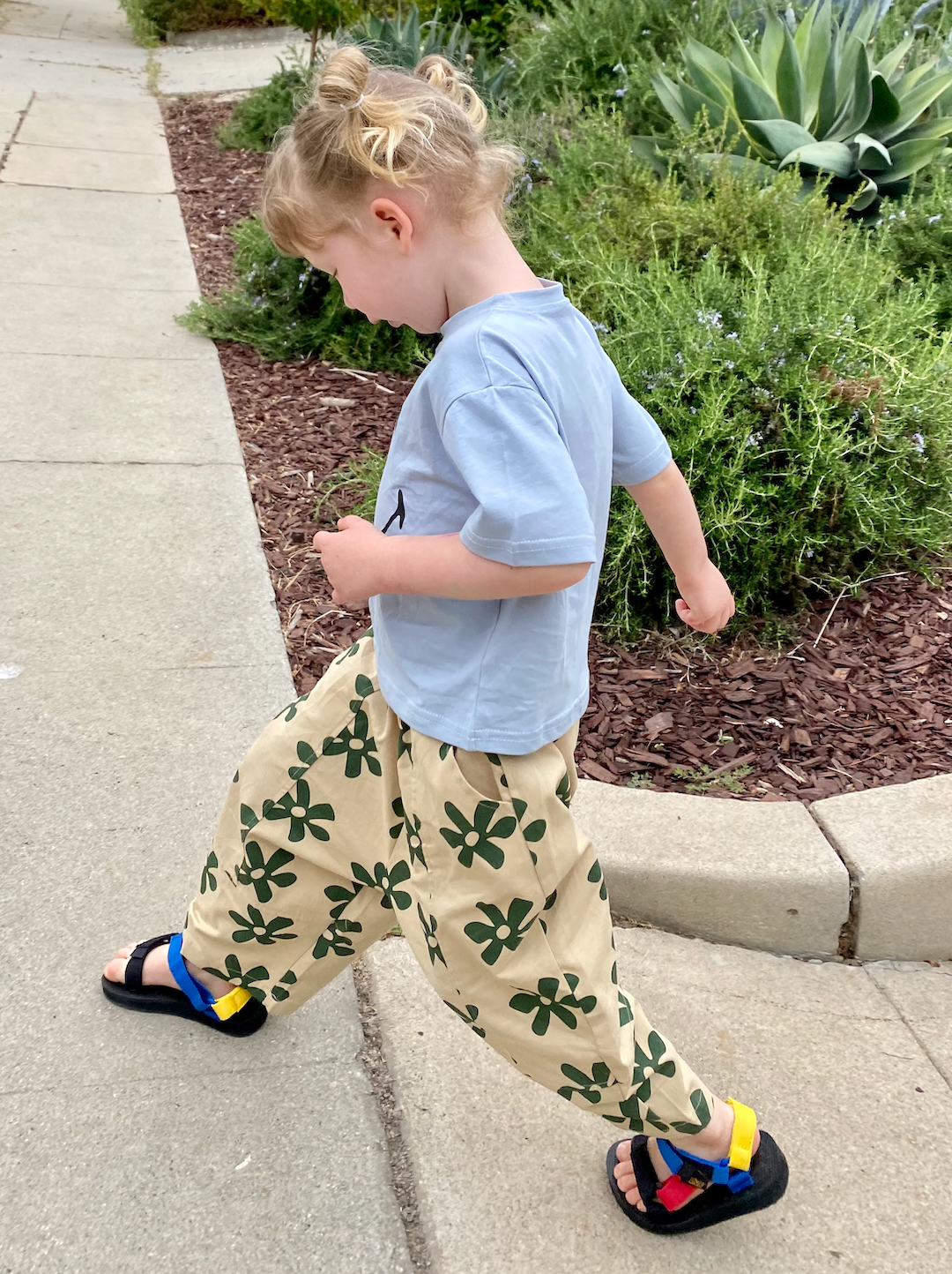 A child walking in a pair of kids' pants, cream with green flowers