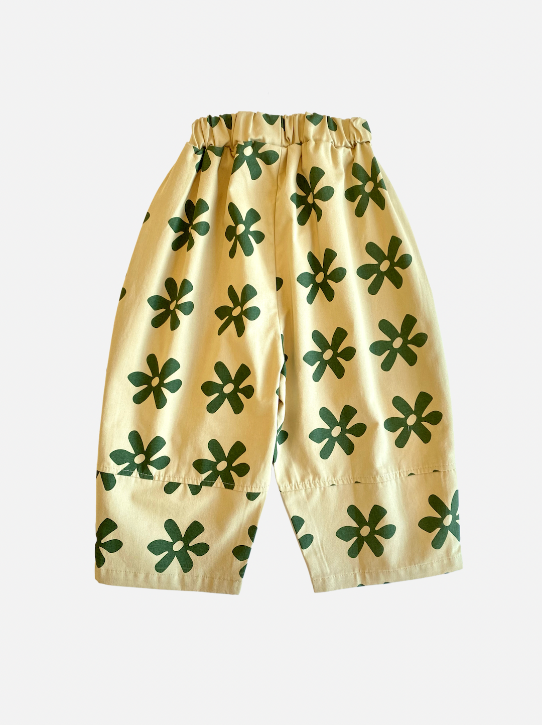 A pair of kids' pants in cream with green flowers