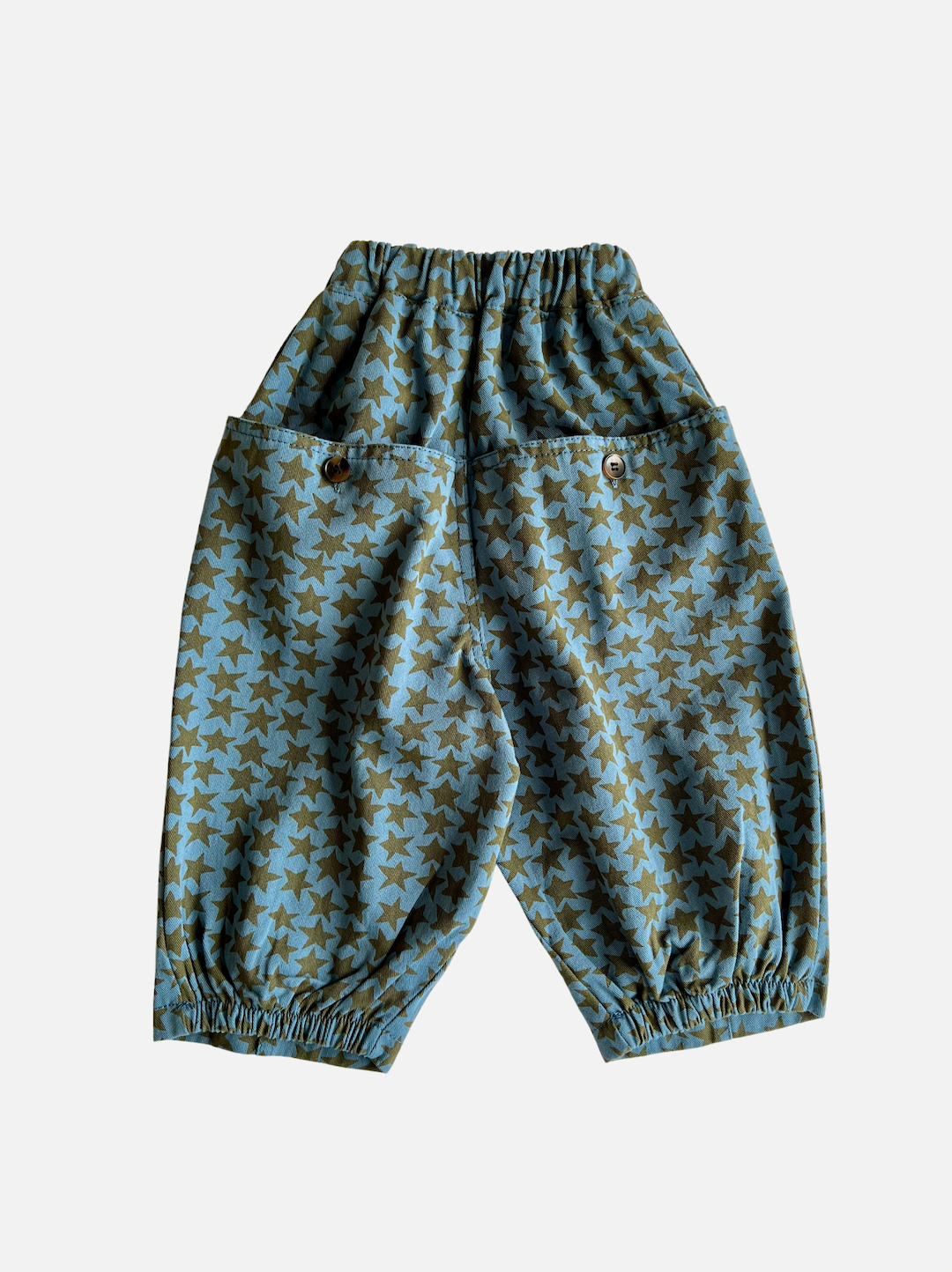 A pair of kids' pants in slate blue with an olive green star pattern, and buttoned back pockets, rear view 