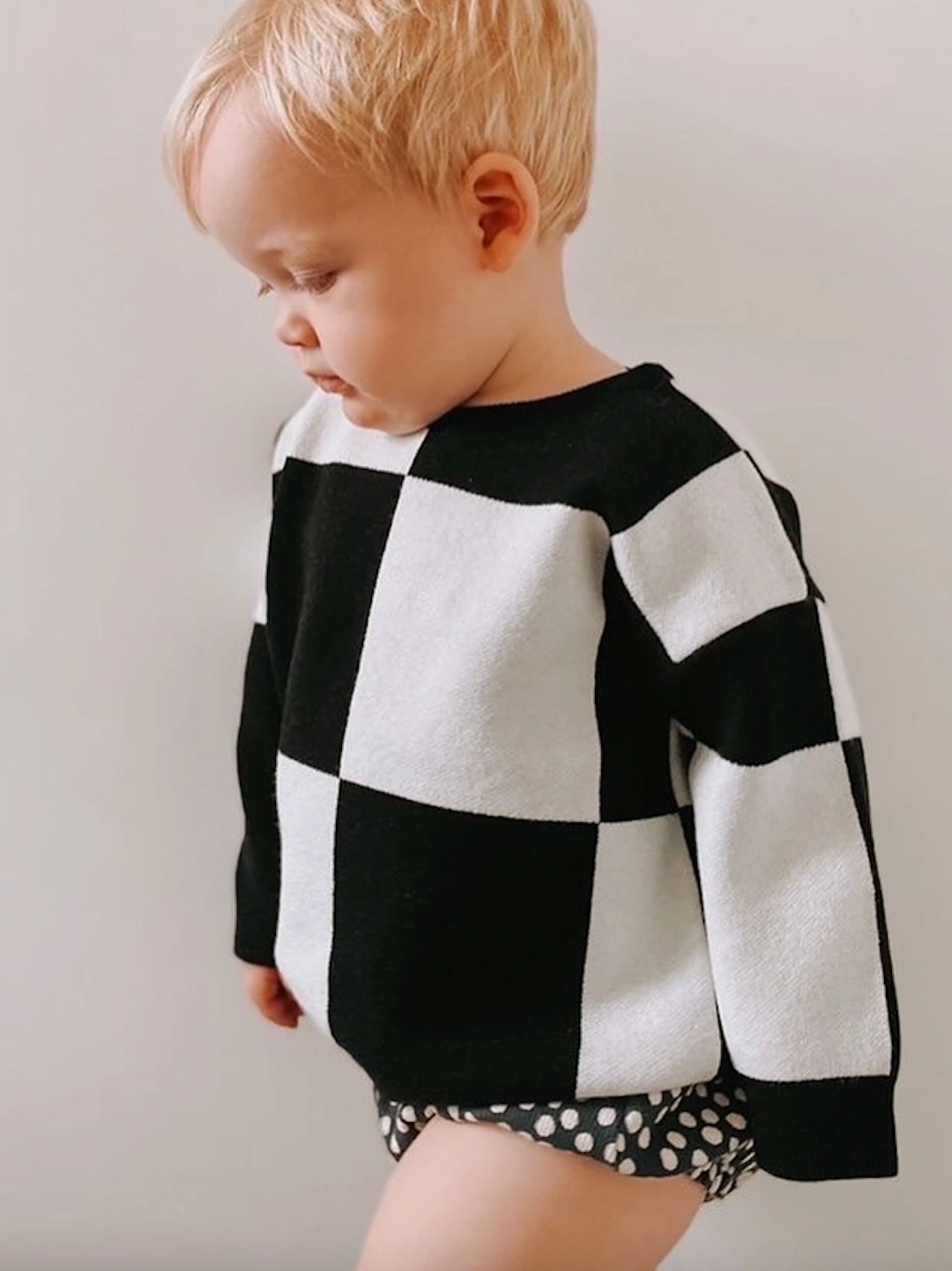 A toddler wearing a kids' sweatshirt in a bold black and white checkerboard