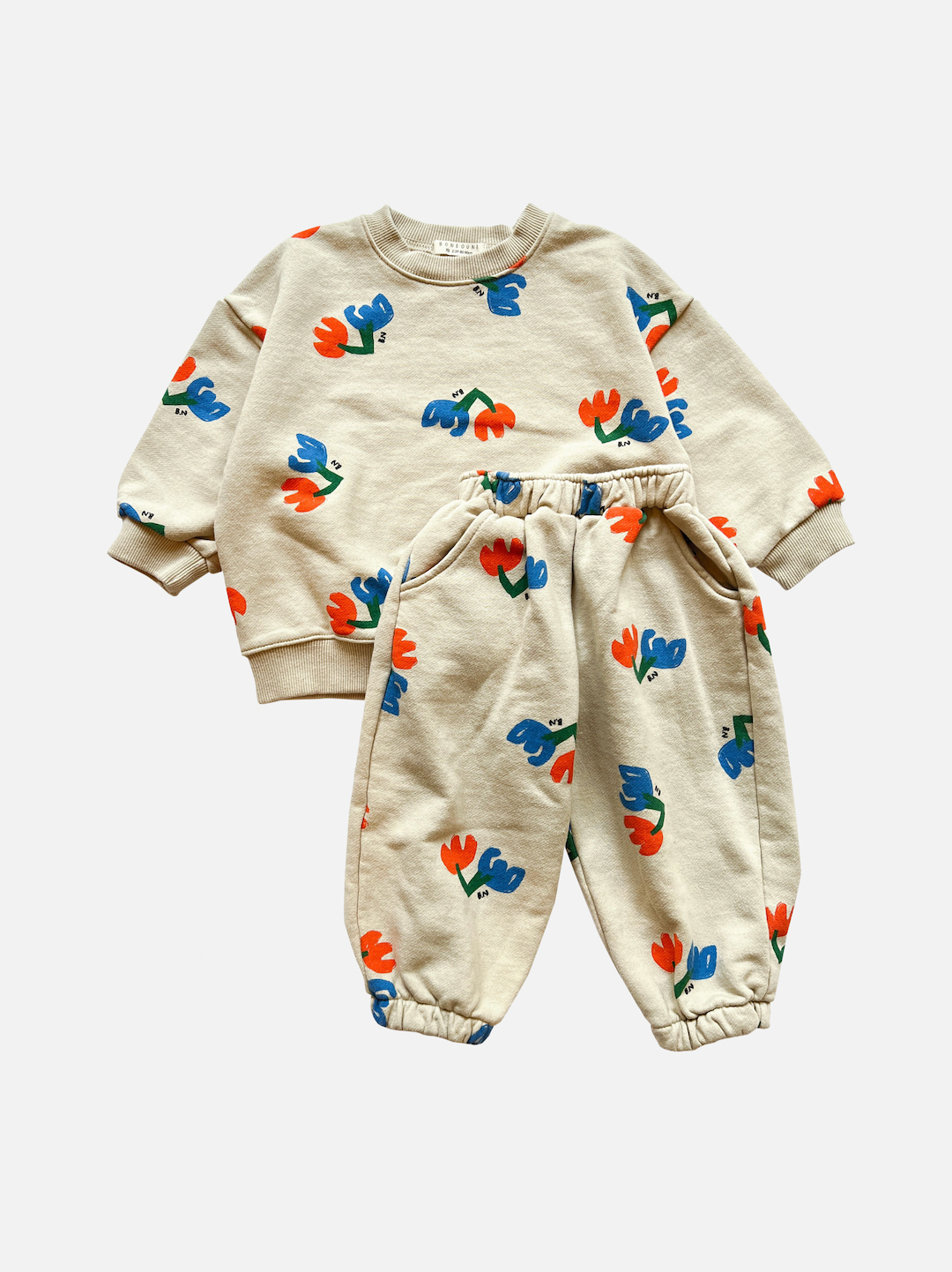 Set of kids' sweatpants and top with blue and red flowers on an ecru background, front view