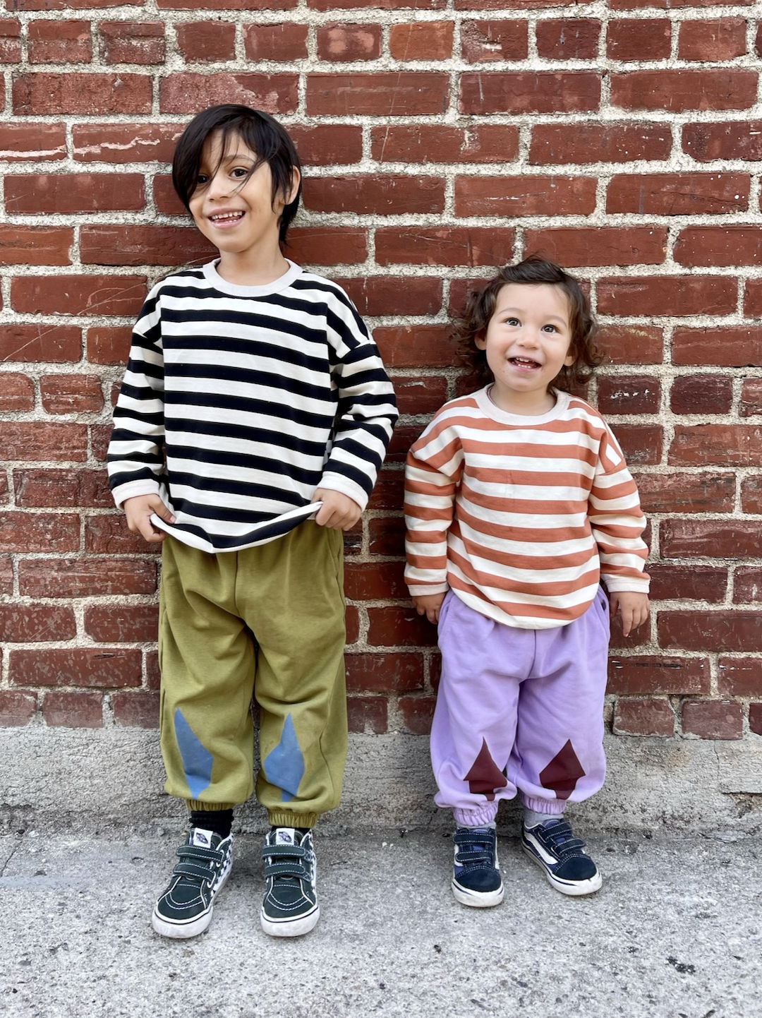 Two children wearing kids' striped tee shirts, one in black and white, the other in peaches and cream