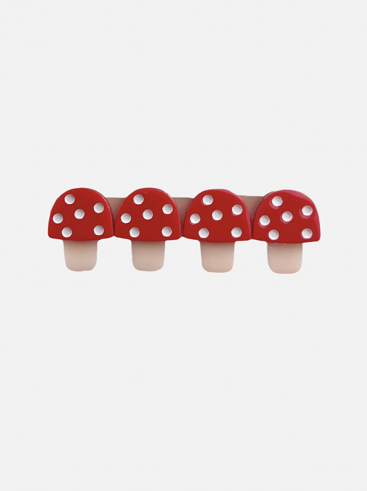 Image of A kids' hairclip featuring four red toadstools with white spots