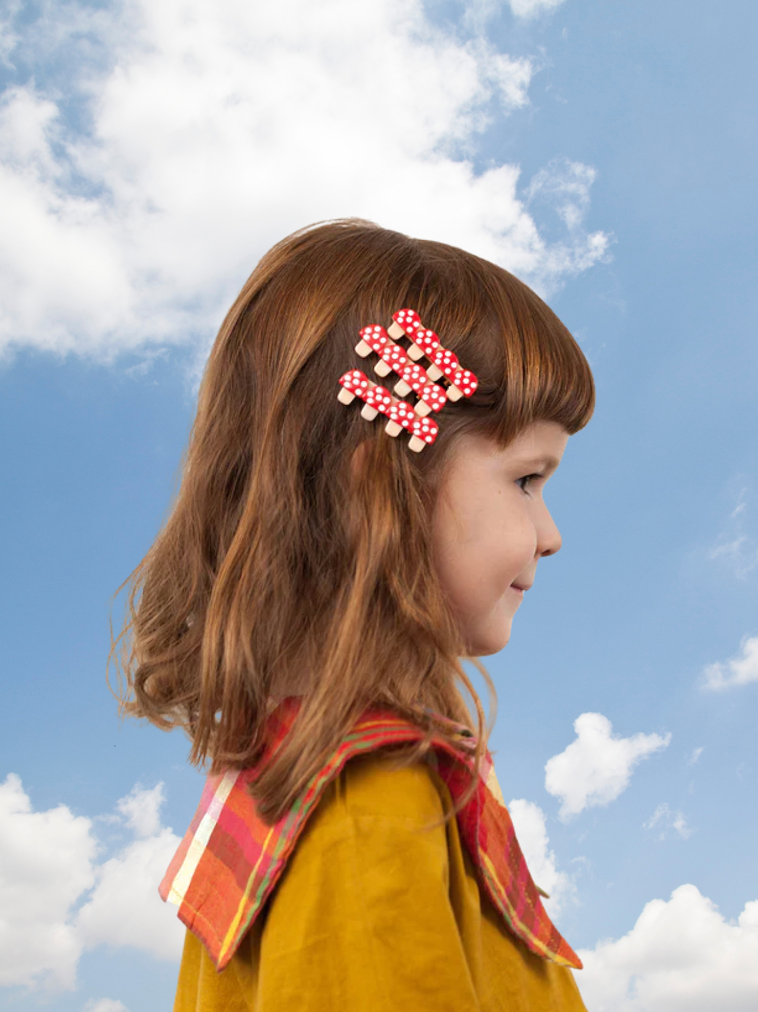 A child wearing three kids' hairclips featuring four red toadstools with white spots