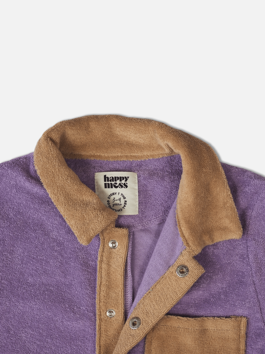 Detail of kids' jumpsuit in pale plum with sand collar, placket over snap fasteners, and pockets